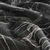 View 4 of product The Turnbull & Asser Black Sketched Pattern Wool Chilcott Scarf features white abstract lines, frayed edges, and is shown loosely knotted on a light gray background.