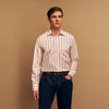 View 1 of product A man poses against a beige backdrop in the Turnbull & Asser Red and Off-White Stripe Cotton Weekend Fit Finch Shirt, styled with dark blue jeans and a brown belt for a timeless look. One hand rests in his pocket as he faces slightly to the side.