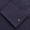 View 4 of product A man stands against a tan background, wearing the Turnbull & Asser Navy Wool Blend Weekend Fit Hayne Shirt tucked into gray dress pants with a black belt and shoes. He has short hair, a neutral expression, and his hands are in his pockets for a casual look.