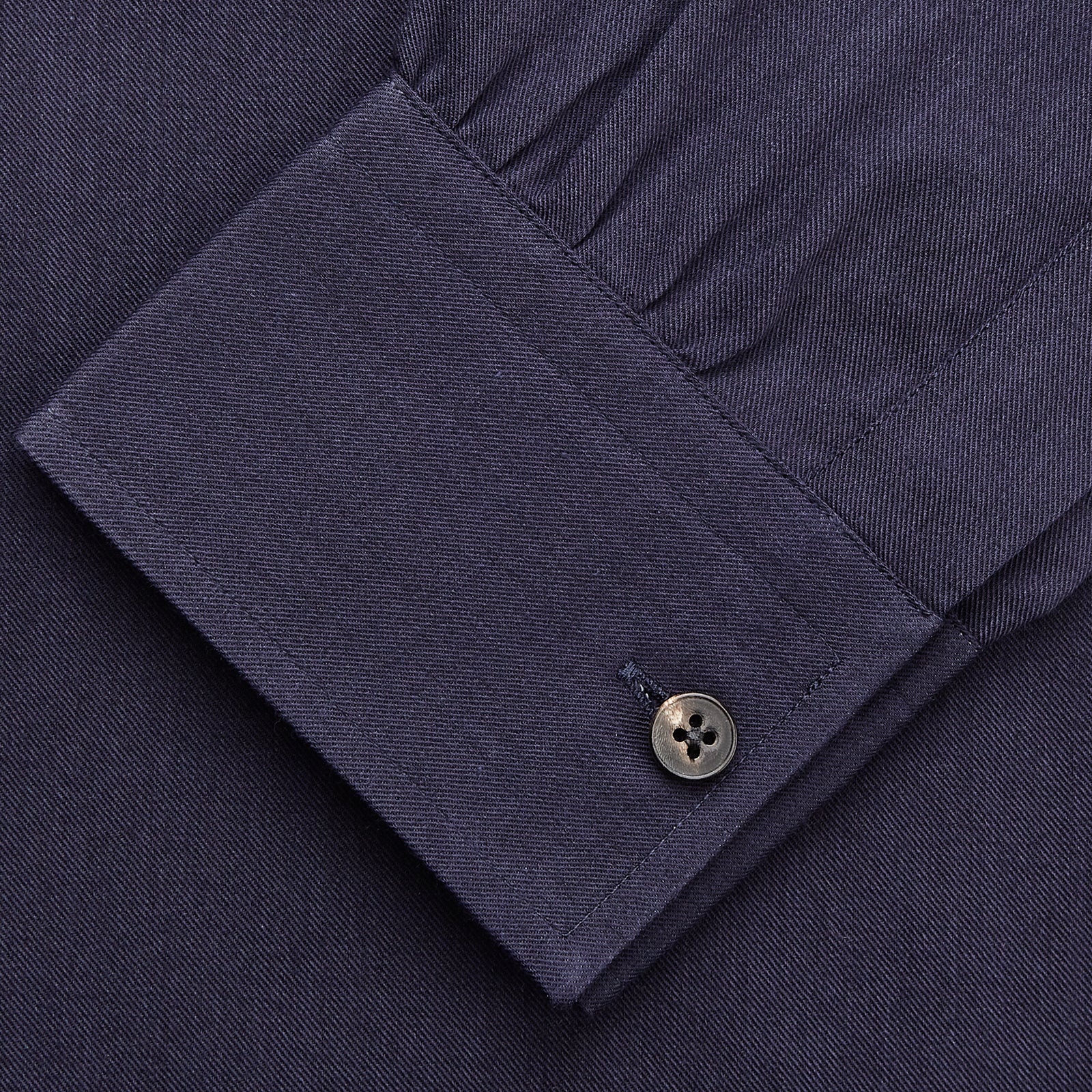 View 4 of product A man stands against a tan background, wearing the Turnbull & Asser Navy Wool Blend Weekend Fit Hayne Shirt tucked into gray dress pants with a black belt and shoes. He has short hair, a neutral expression, and his hands are in his pockets for a casual look.