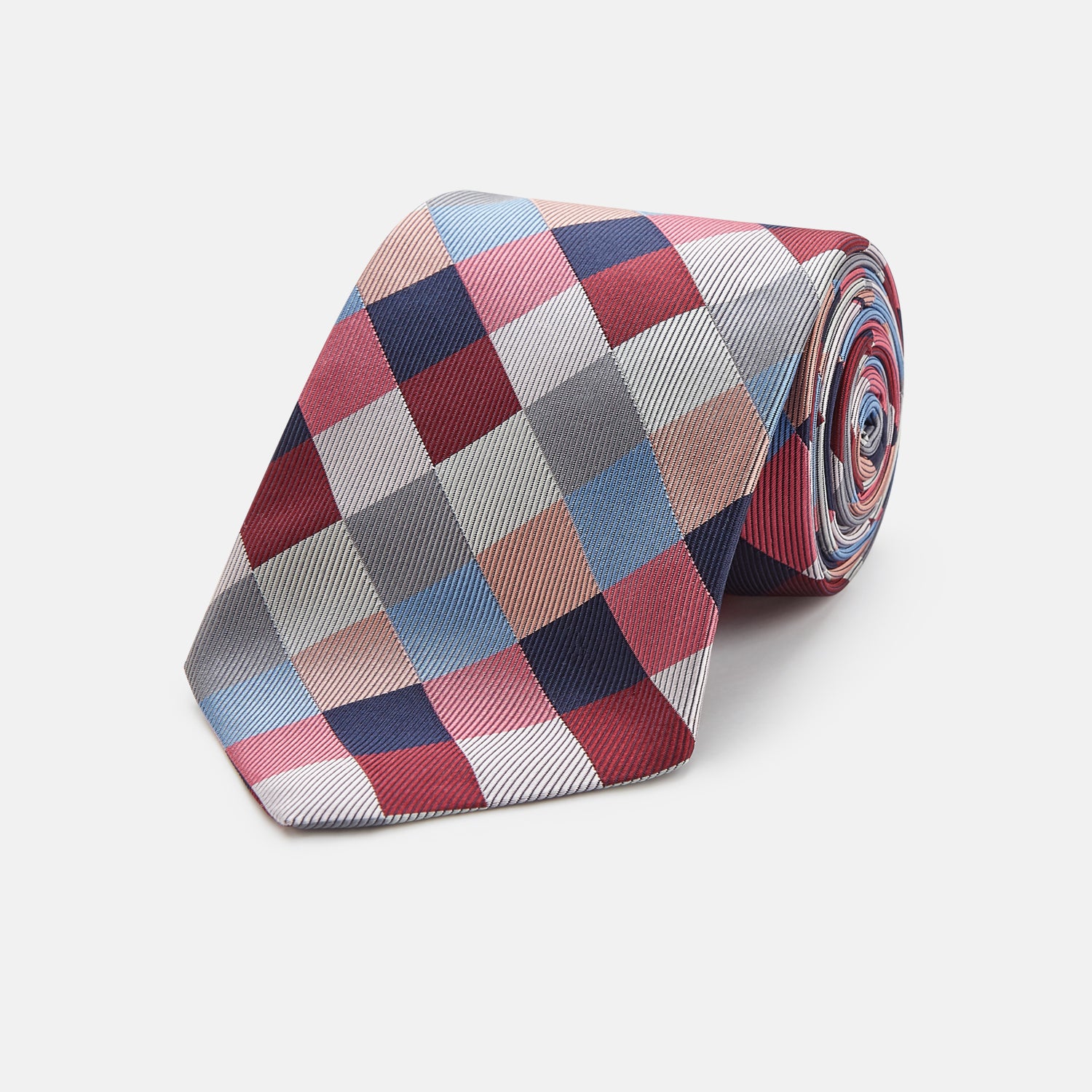 View 1 of product The Turnbull & Asser Pink and Blue Checkerboard Silk Tie is shown rolled up, highlighting its pink, blue, grey, and white pattern against a plain white background.