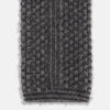 View 4 of product The Grey Multi Cashmere Knitted Tie by Turnbull & Asser features a textured checkered pattern, rolled and displayed on a white background—a refined menswear essential.