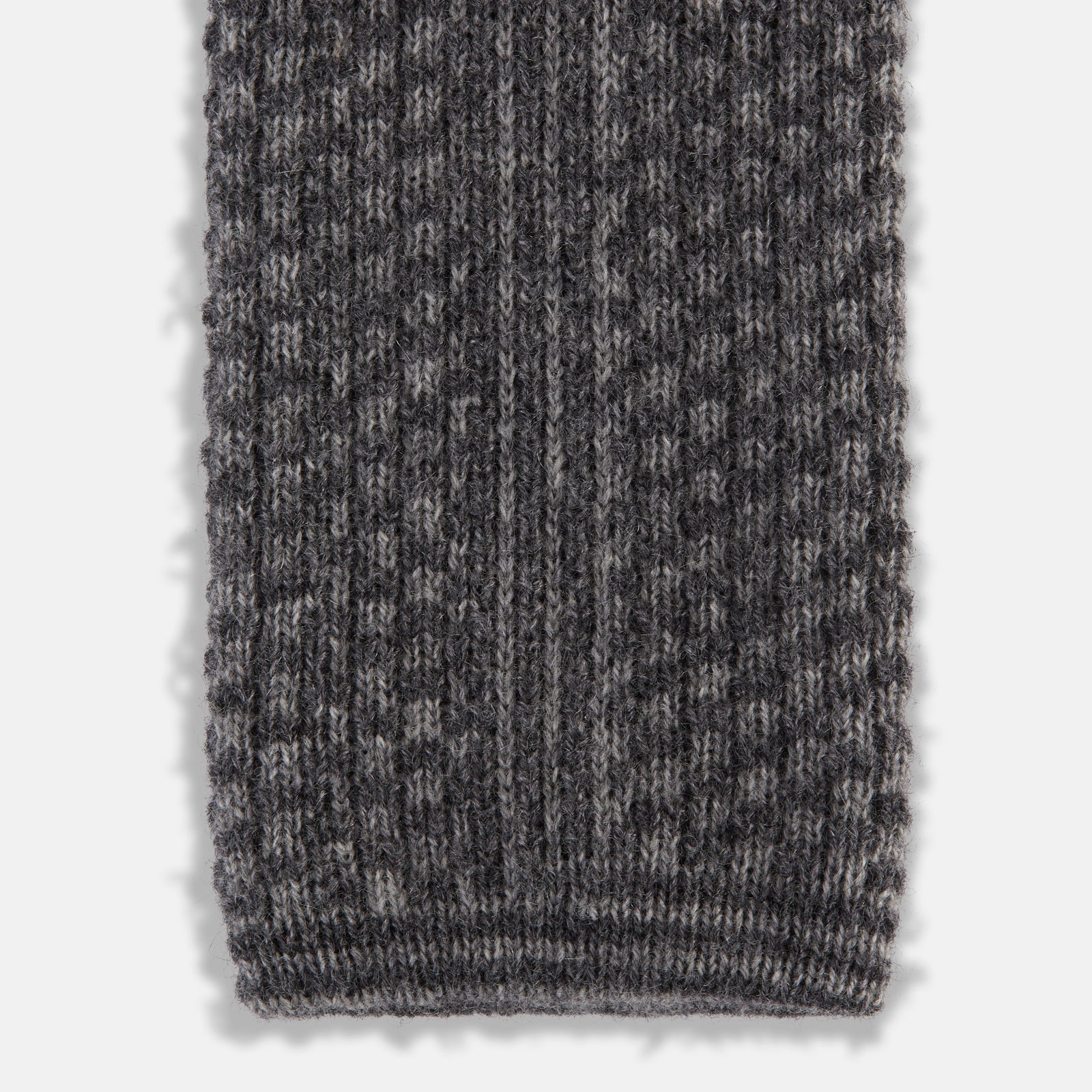 View 4 of product The Grey Multi Cashmere Knitted Tie by Turnbull & Asser features a textured checkered pattern, rolled and displayed on a white background—a refined menswear essential.