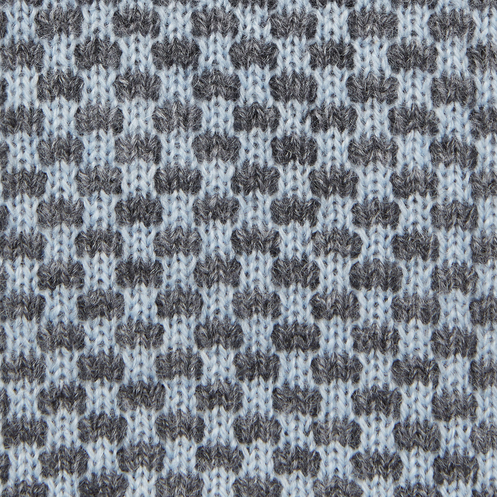 The Turnbull & Asser Pale Blue Multi Cashmere Knitted Tie features a subtle checkered pattern in black and light blue, making it a refined addition to your menswear collection. Shown rolled up on a plain white background.