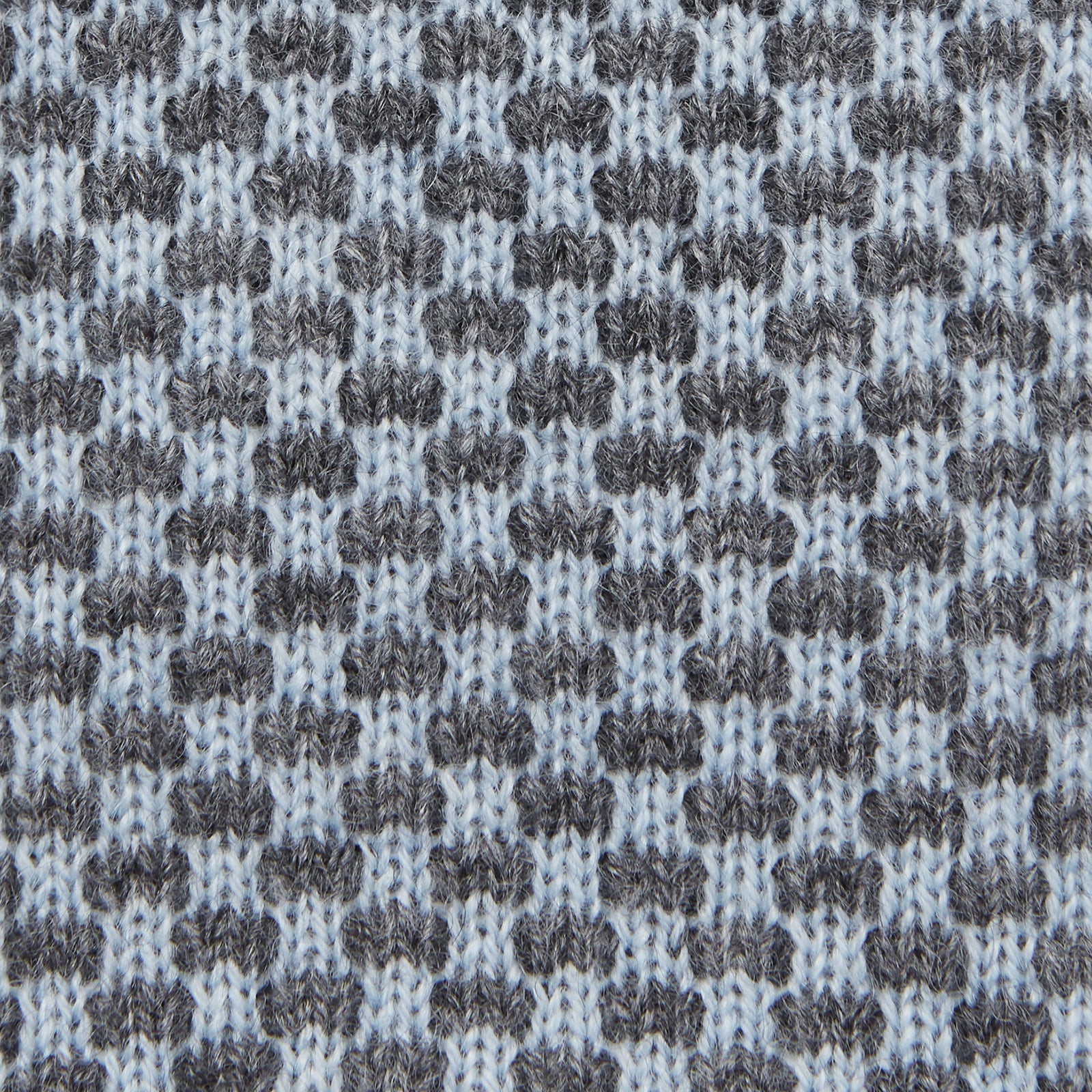 View 3 of product The Turnbull & Asser Pale Blue Multi Cashmere Knitted Tie features a subtle checkered pattern in black and light blue, making it a refined addition to your menswear collection. Shown rolled up on a plain white background.