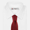 View 2 of product The Turnbull & Asser Red Multi Cashmere Knitted Tie, featuring a textured dark red design, is displayed rolled up on a plain white background.