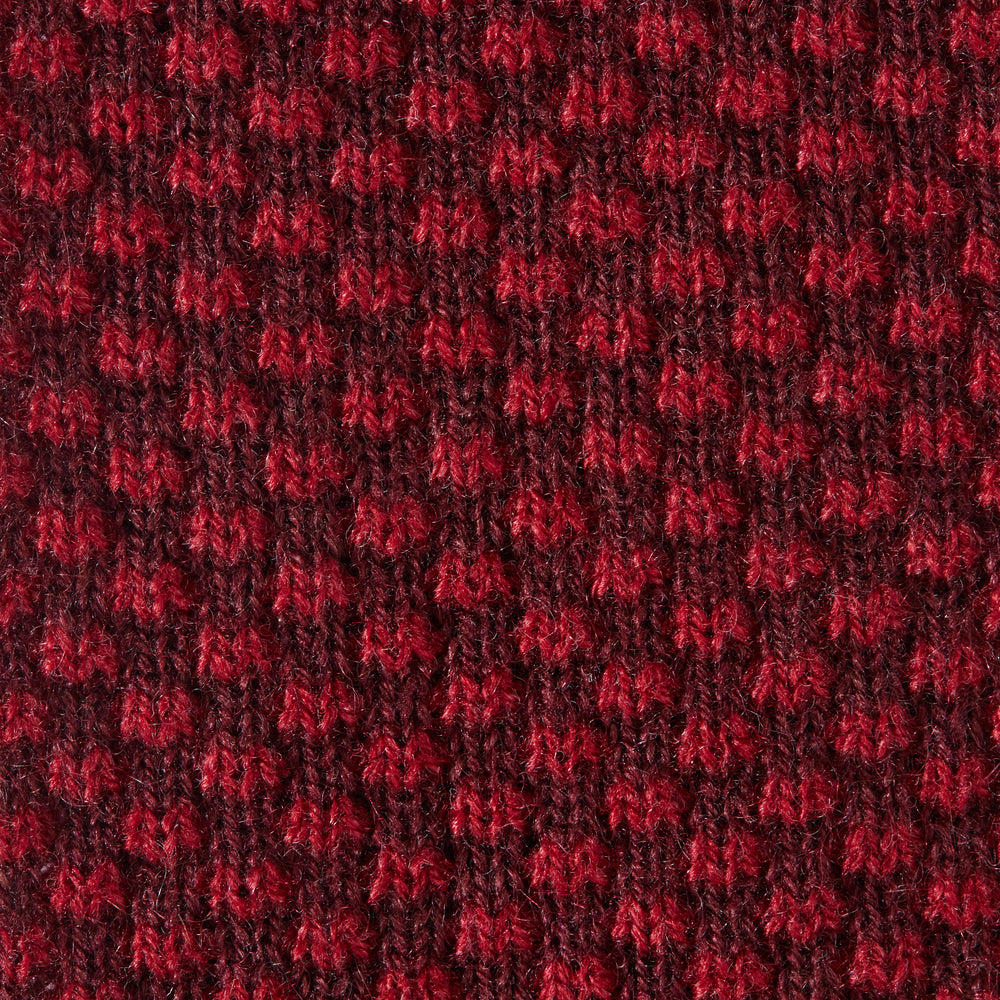 The Turnbull & Asser Red Multi Cashmere Knitted Tie, featuring a textured dark red design, is displayed rolled up on a plain white background.