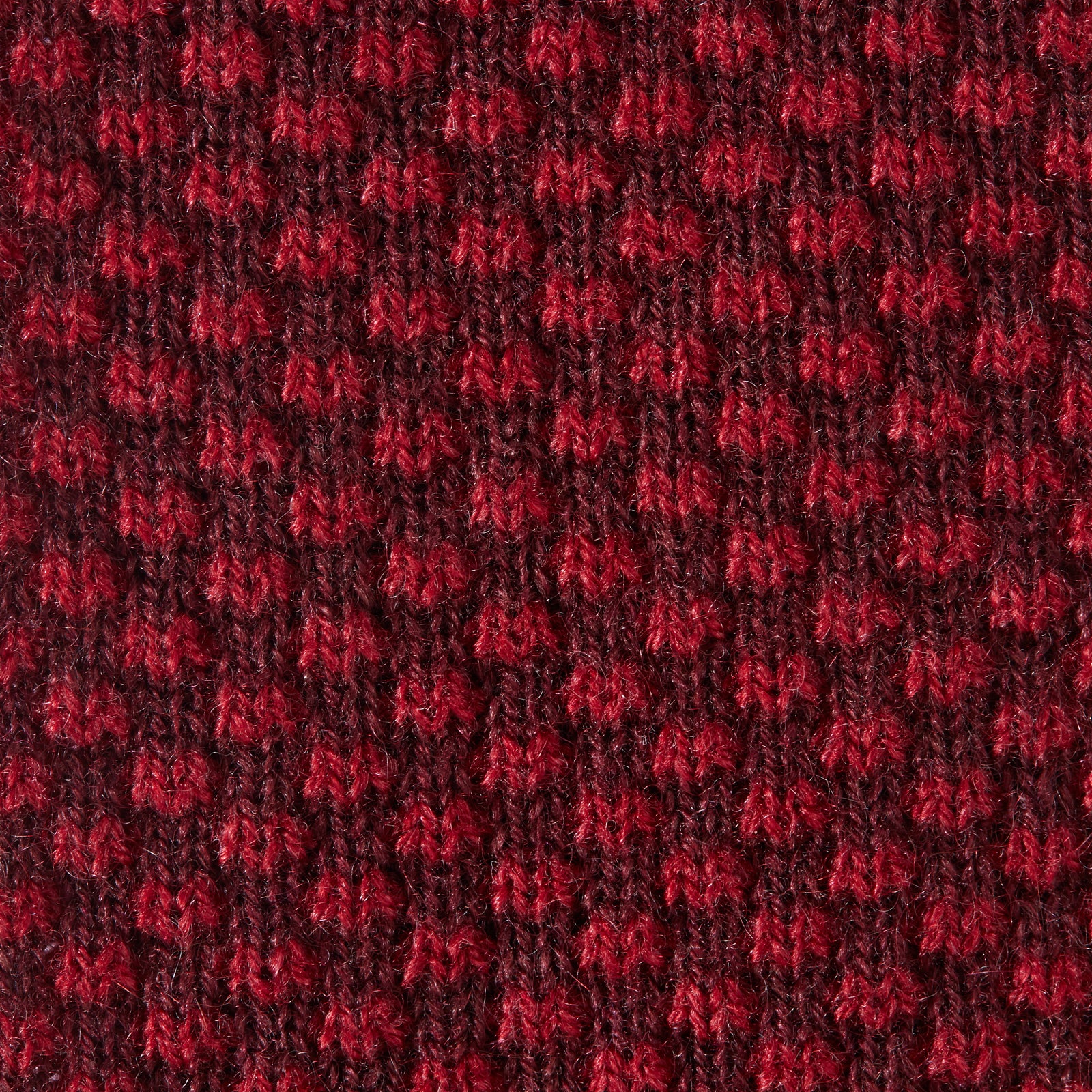 View 3 of product The Turnbull & Asser Red Multi Cashmere Knitted Tie, featuring a textured dark red design, is displayed rolled up on a plain white background.