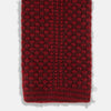 View 4 of product The Turnbull & Asser Red Multi Cashmere Knitted Tie, featuring a textured dark red design, is displayed rolled up on a plain white background.
