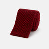 View 1 of product The Turnbull & Asser Red Multi Cashmere Knitted Tie, featuring a textured dark red design, is displayed rolled up on a plain white background.