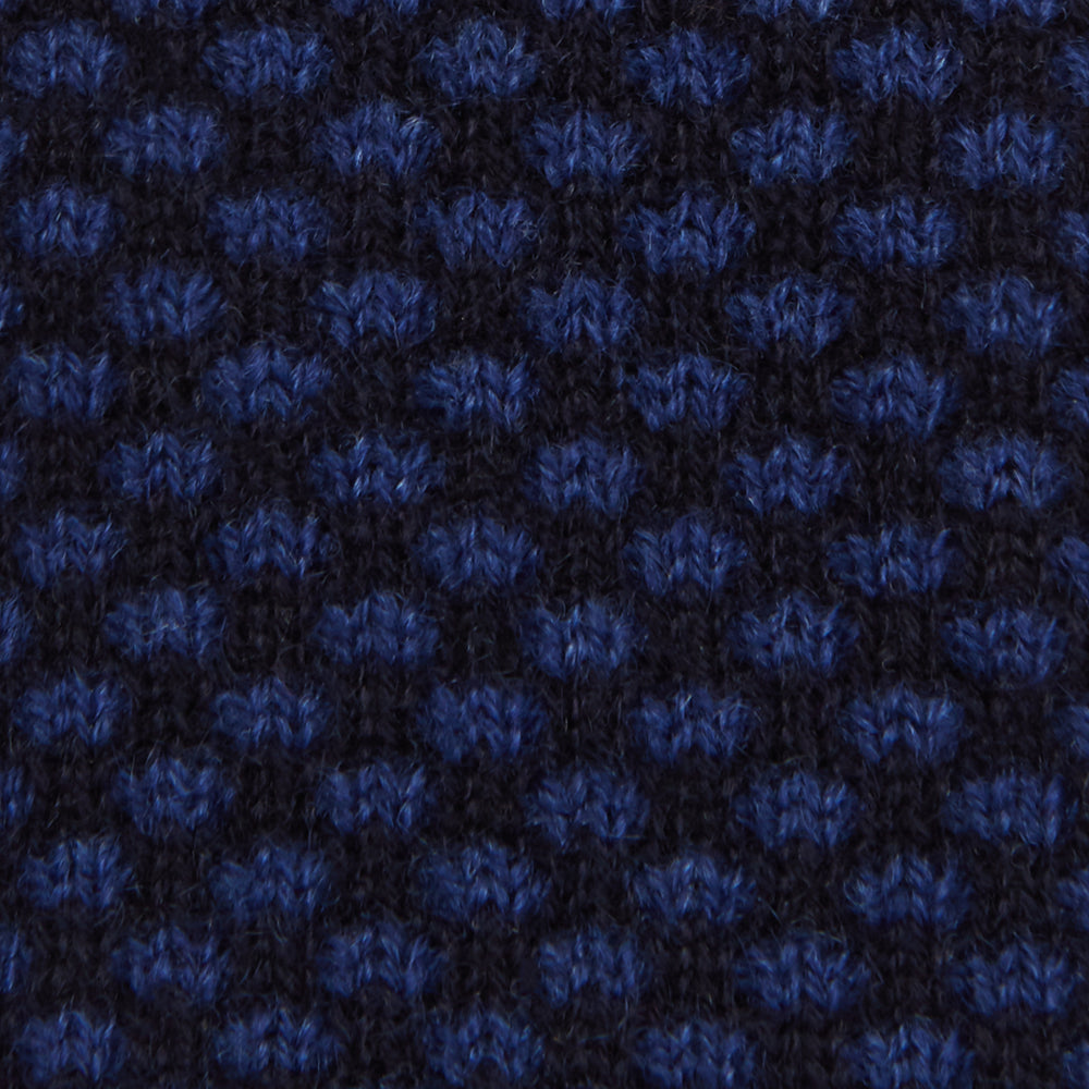 The Turnbull & Asser Navy Multi Cashmere Knitted Tie features a subtle black checkered pattern and is shown rolled up against a plain light background.