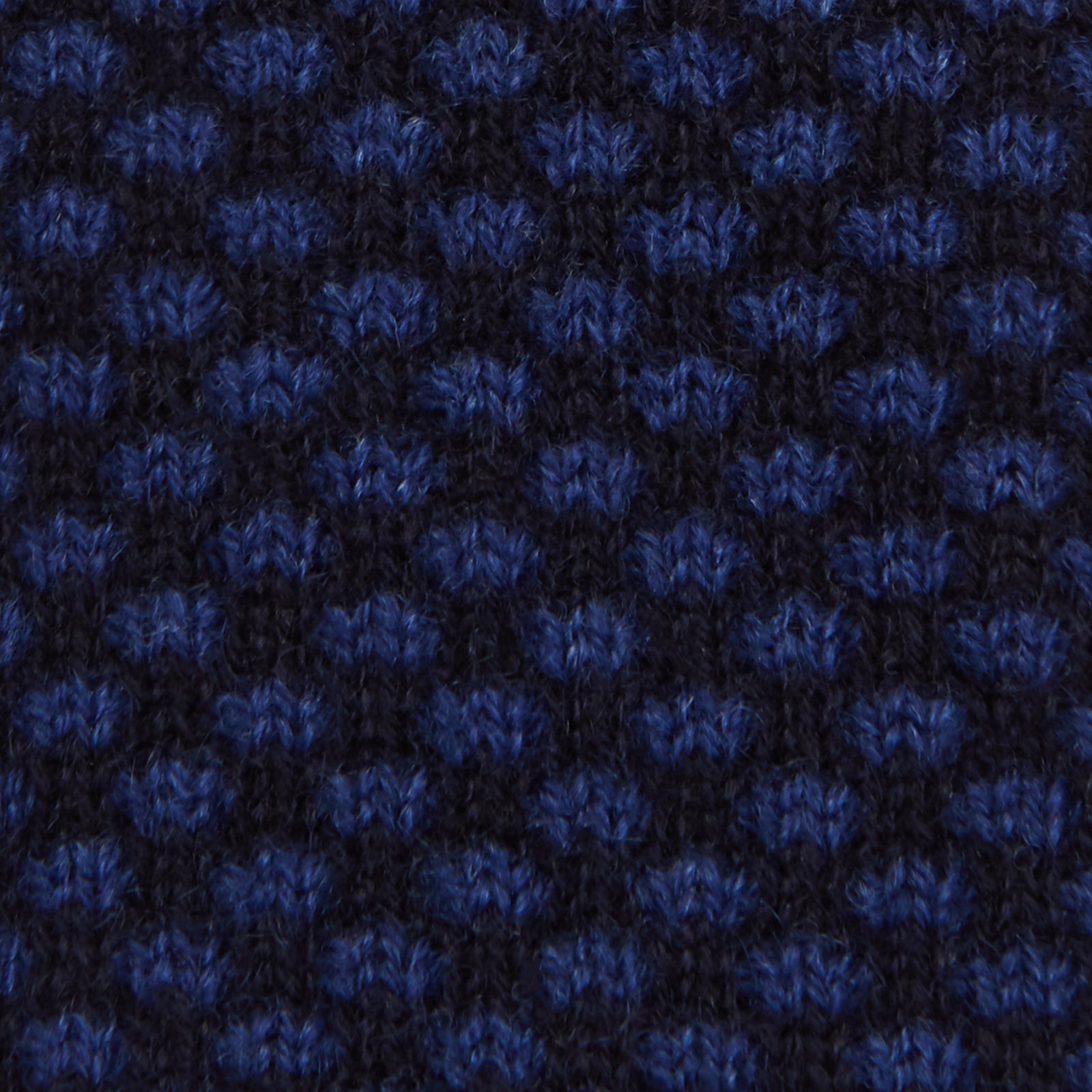 View 3 of product The Turnbull & Asser Navy Multi Cashmere Knitted Tie features a subtle black checkered pattern and is shown rolled up against a plain light background.