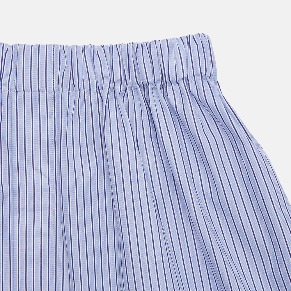 Turnbull & Asser's Blue and Navy Halo Stripe Cotton Godfrey Boxer Shorts feature thin vertical navy stripes on a light blue background with an elastic waistband—luxury sleepwear crafted for ultimate comfort.