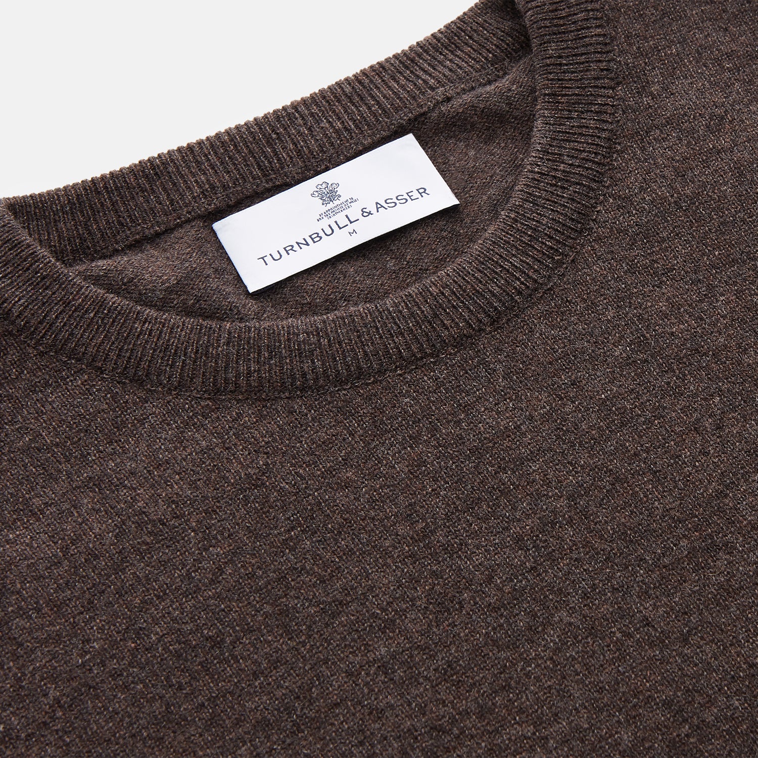 View 2 of product The Turnbull & Asser Brown Cashmere Glenn Jumper is a classic menswear piece with a crew neck and ribbed cuffs, collar, and hem. It’s laid flat on a white background, showcasing its timeless long-sleeved design.