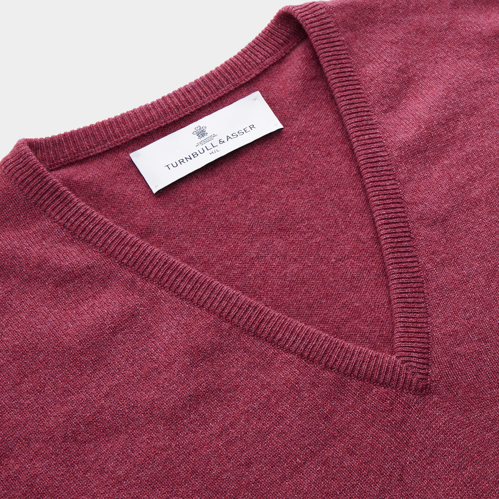 The Turnbull & Asser Soft Burgundy Cashmere V-neck Paden Jumper is displayed flat on a white background, showing off its soft texture and subtle ribbed cuffs and hem.