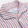 View 2 of product The Turnbull & Asser Red and Blue Stripe Cotton Quin Pyjamas feature a collared, long-sleeve button-up top with black piping and chest pocket, paired with matching striped pants for luxurious comfort and style.
