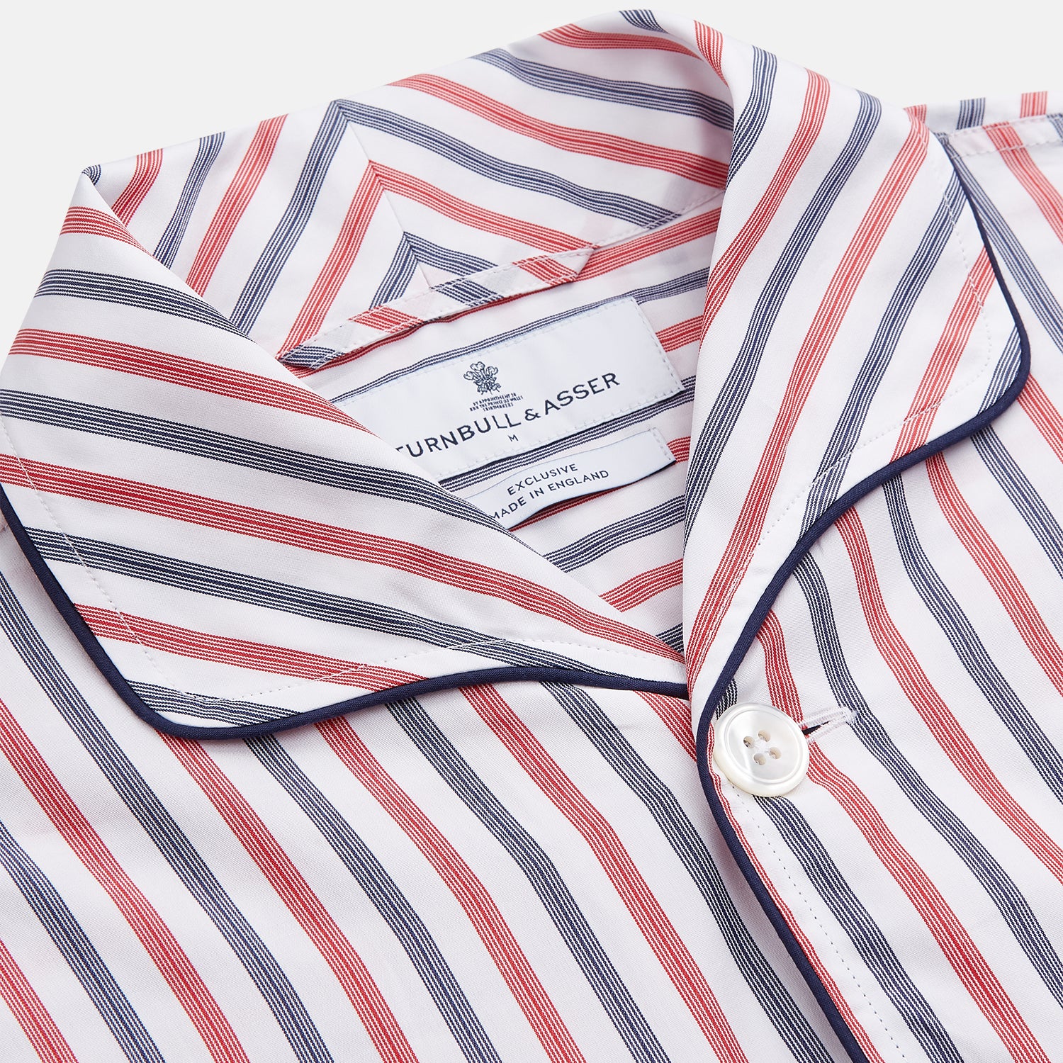 View 2 of product The Turnbull & Asser Red and Blue Stripe Cotton Quin Pyjamas feature a collared, long-sleeve button-up top with black piping and chest pocket, paired with matching striped pants for luxurious comfort and style.