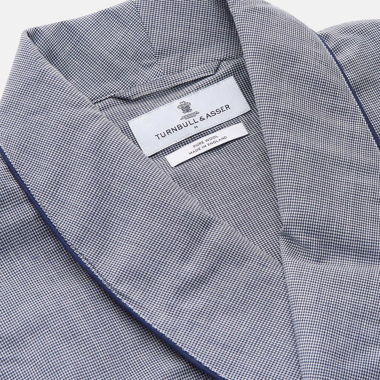 View 4 of product The Navy Houndstooth Wool Arnold Gown by Turnbull & Asser features a shawl collar, front chest pocket, long sleeves, and a matching fabric belt tied at the waist.