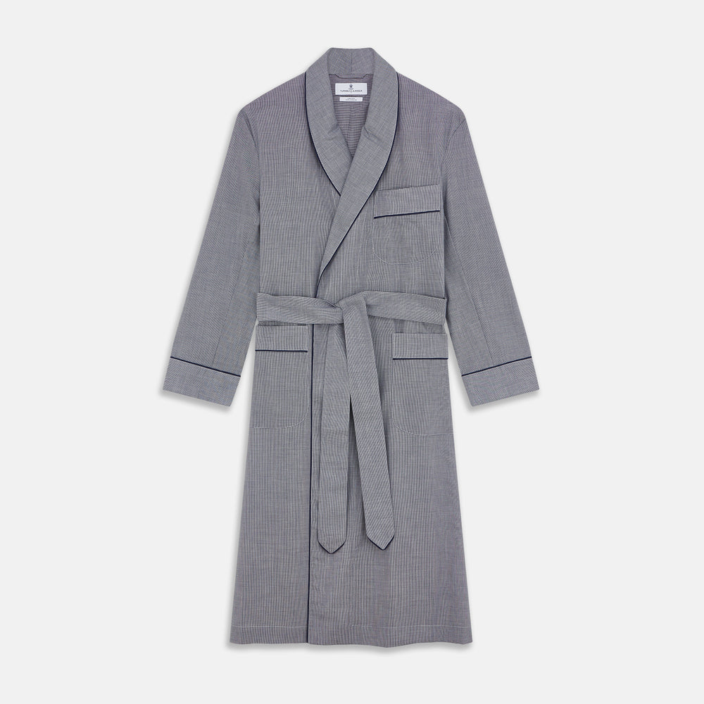 The Navy Houndstooth Wool Arnold Gown by Turnbull & Asser features a shawl collar, front chest pocket, long sleeves, and a matching fabric belt tied at the waist.