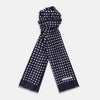 View 1 of product The Turnbull & Asser Navy and Cream Spotted Silk and Wool Scarf features white polka dots, a visible label, slightly frayed edges, and a hand-printed look for unique style.