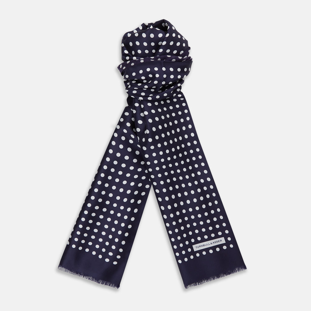 The Turnbull & Asser Navy and Cream Spotted Silk and Wool Scarf features white polka dots, a visible label, slightly frayed edges, and a hand-printed look for unique style.