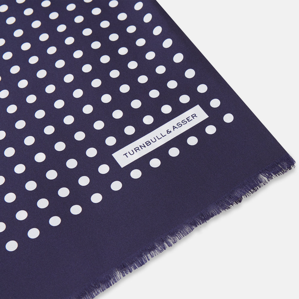 The Turnbull & Asser Navy and Cream Spotted Silk and Wool Scarf features white polka dots, a visible label, slightly frayed edges, and a hand-printed look for unique style.