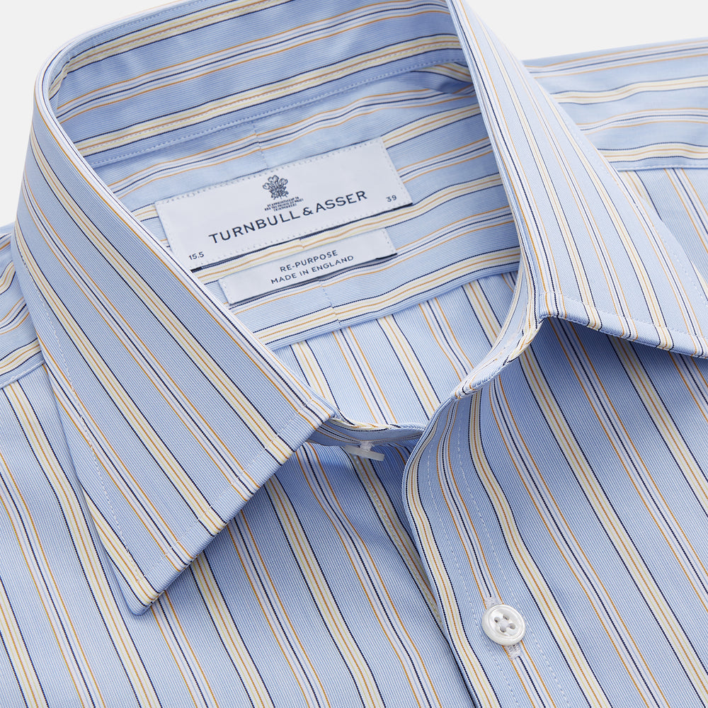 The Turnbull & Asser Blue and Yellow Multi Stripe Cotton Regular Fit Mayfair Shirt features thin vertical stripes in white, blue, and tan, a collared design with white buttons—an essential formal staple for any man’s wardrobe.
