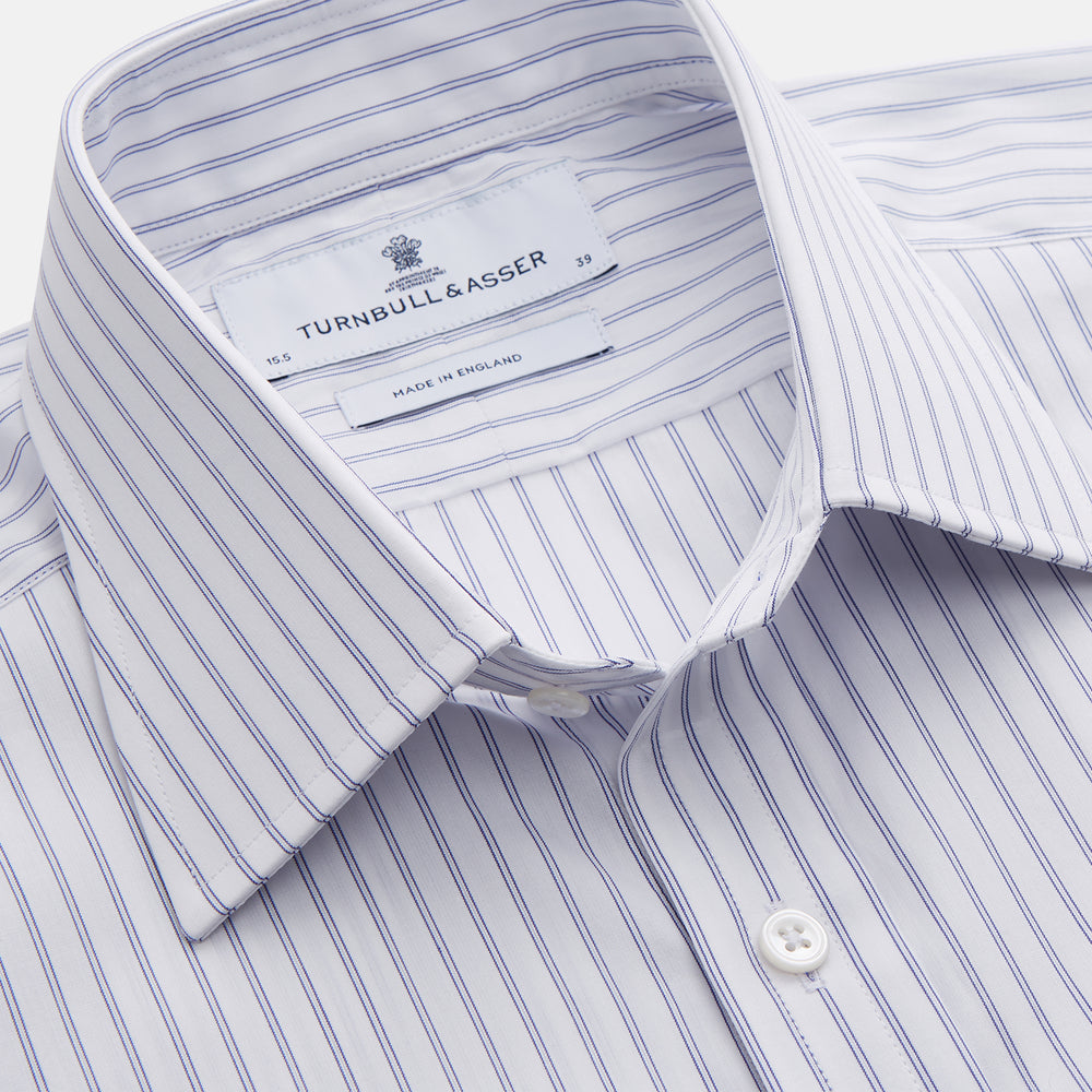 The Turnbull & Asser White and Blue Halo Stripe Cotton Regular Fit Mayfair Shirt features thin vertical stripes, a classic collar, and cuffed long sleeves—an essential men's formal shirt shown laid flat on a white background.