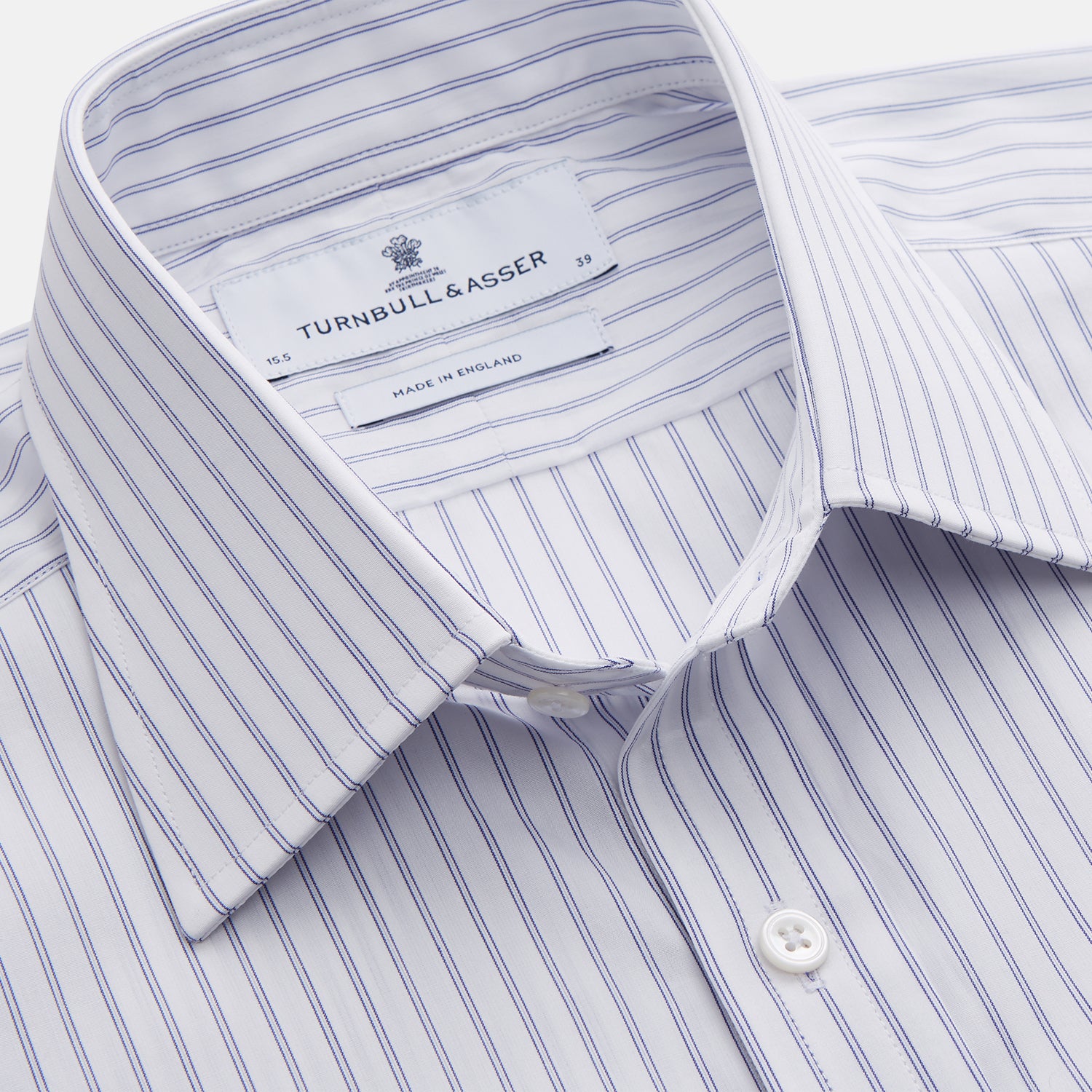 View 4 of product The Turnbull & Asser White and Blue Halo Stripe Cotton Regular Fit Mayfair Shirt features thin vertical stripes, a classic collar, and cuffed long sleeves—an essential men's formal shirt shown laid flat on a white background.