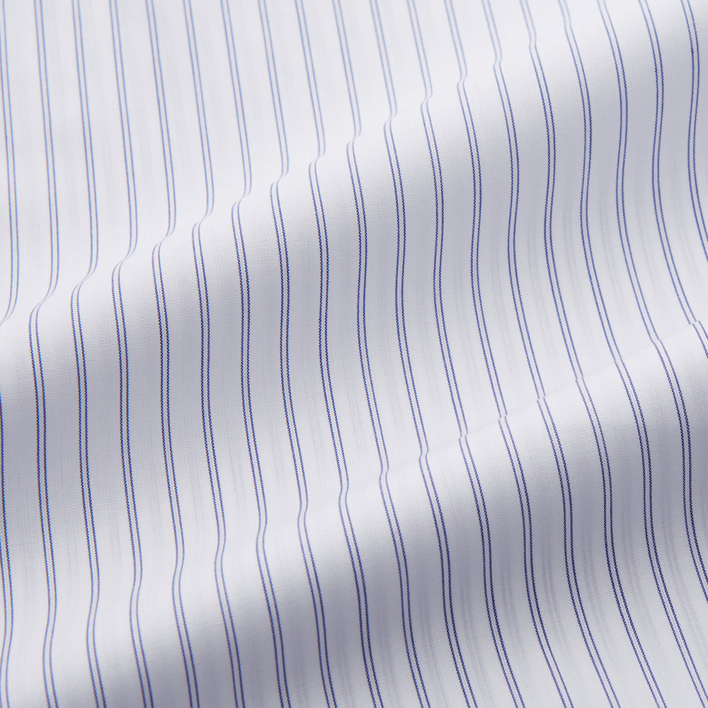 The Turnbull & Asser White and Blue Halo Stripe Cotton Regular Fit Mayfair Shirt features thin vertical stripes, a classic collar, and cuffed long sleeves—an essential men's formal shirt shown laid flat on a white background.
