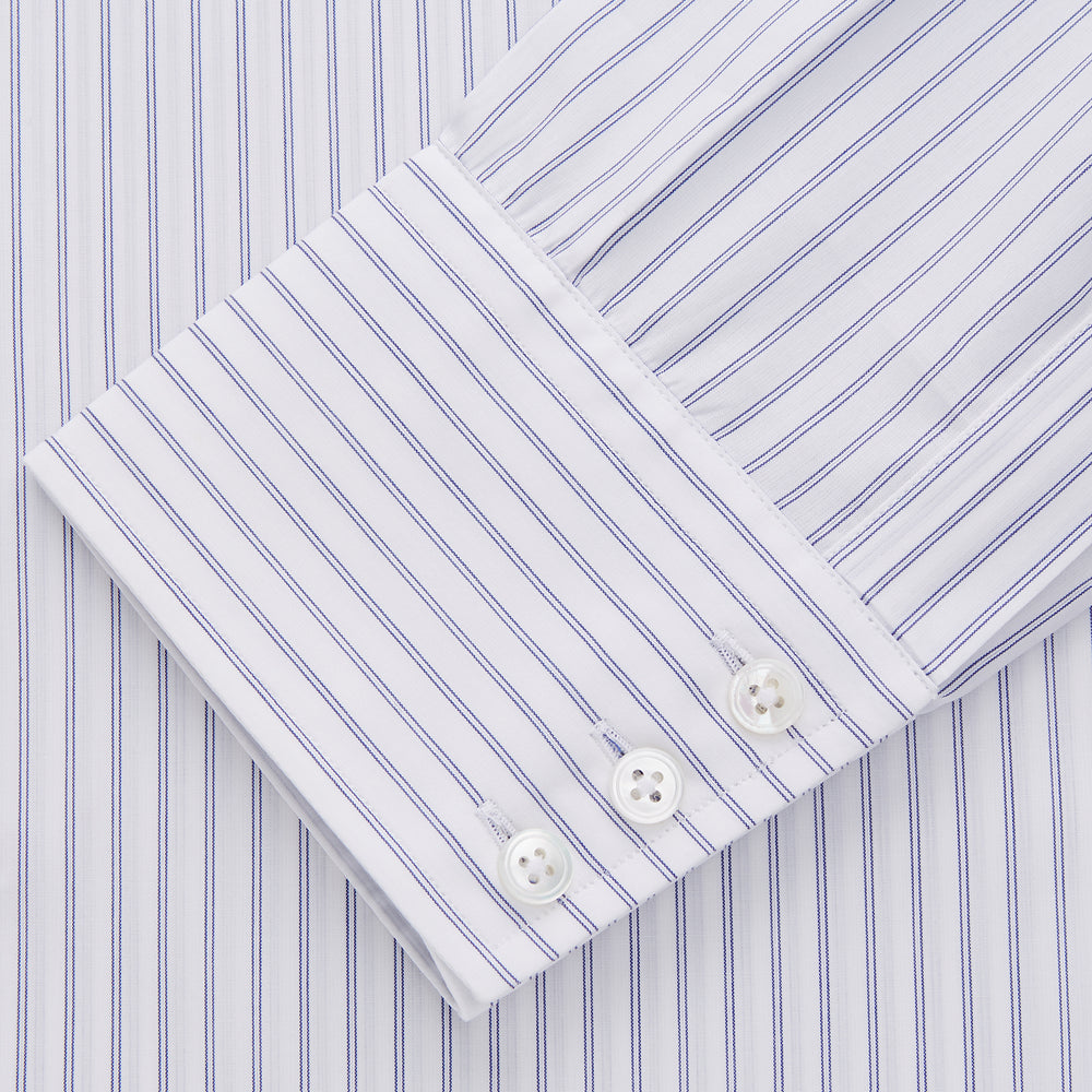 The Turnbull & Asser White and Blue Halo Stripe Cotton Regular Fit Mayfair Shirt features thin vertical stripes, a classic collar, and cuffed long sleeves—an essential men's formal shirt shown laid flat on a white background.