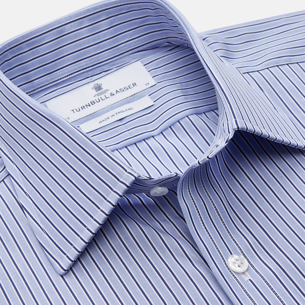 The Blue and Navy Halo Stripe Cotton Regular Fit Mayfair Shirt by Turnbull & Asser features classic styling with vertical stripes, a button-up front, and cuffed sleeves—an essential men's wardrobe piece.