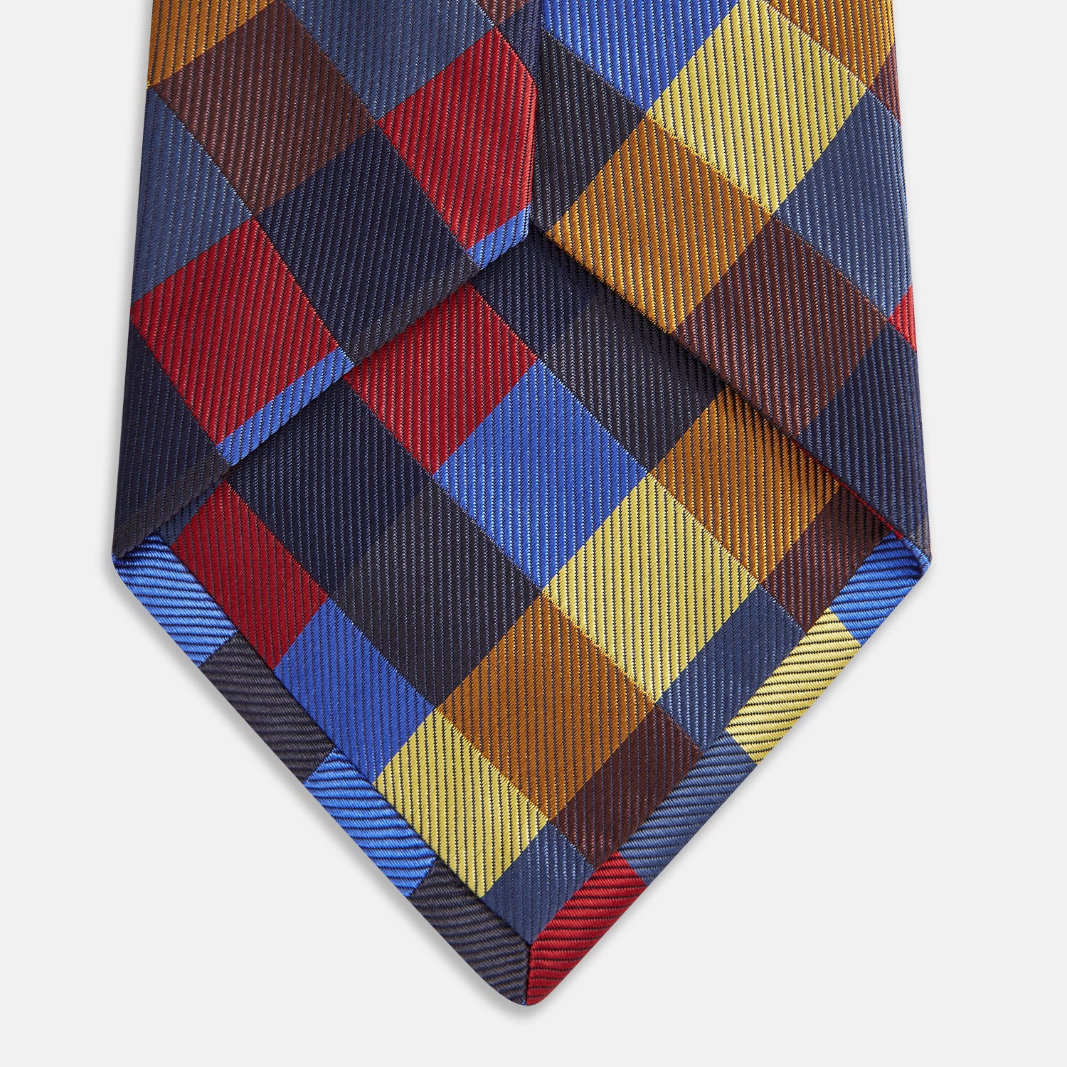 View 3 of product The Turnbull & Asser Blue, Red and Yellow Checker Silk Tie features a bold checkered pattern in red, blue, yellow, brown, and black tones, shown rolled up against a white background.