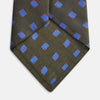 View 3 of product The Turnbull & Asser Dark Green and Blue Tile Silk Tie showcases a classic tile pattern with blue and red squares on herringbone fabric.