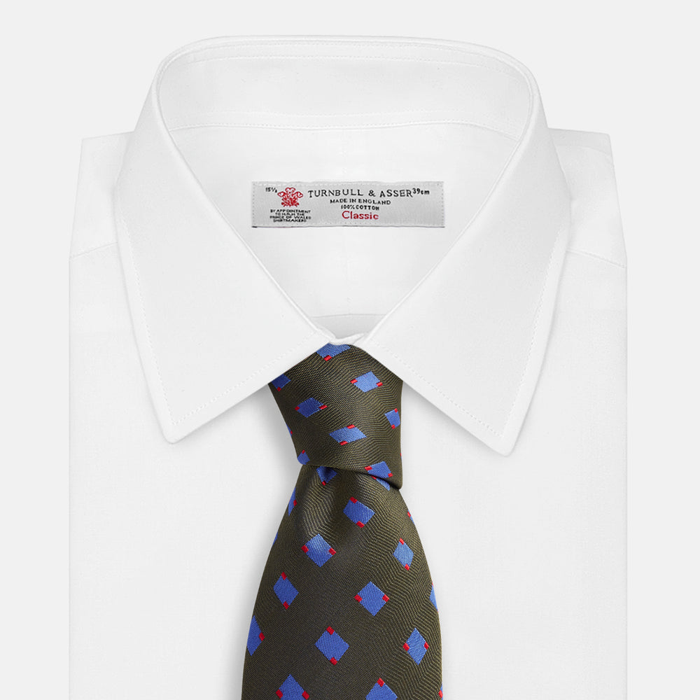 The Turnbull & Asser Dark Green and Blue Tile Silk Tie showcases a classic tile pattern with blue and red squares on herringbone fabric.