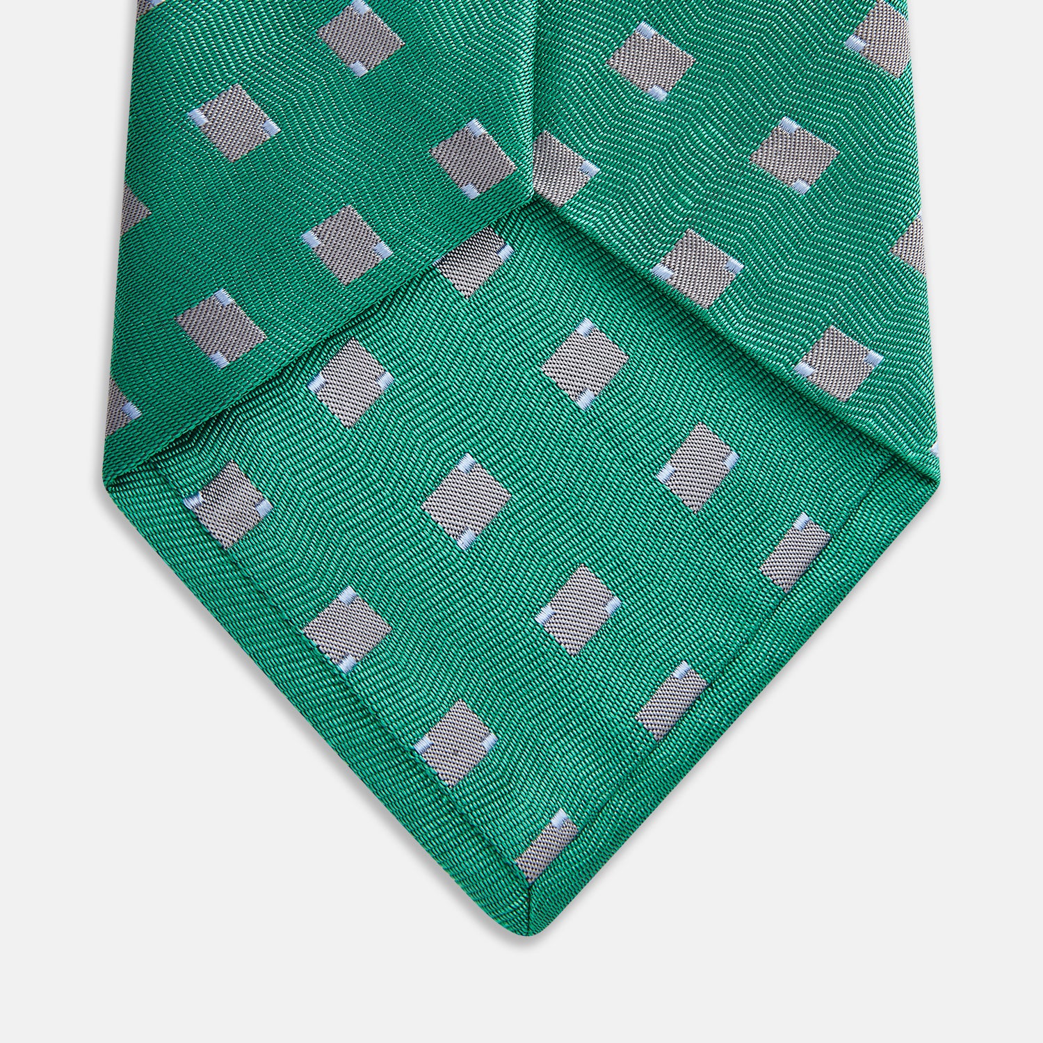 View 2 of product The Turnbull & Asser Kelly Green and Grey Tile Silk Tie features a subtle chevron texture and classic grey tile pattern, displayed rolled on a white background.
