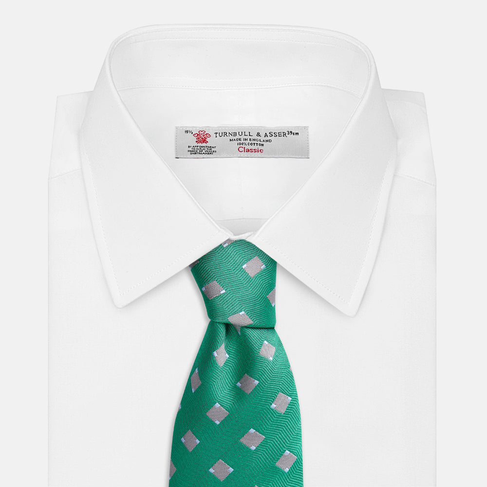 The Turnbull & Asser Kelly Green and Grey Tile Silk Tie features a subtle chevron texture and classic grey tile pattern, displayed rolled on a white background.