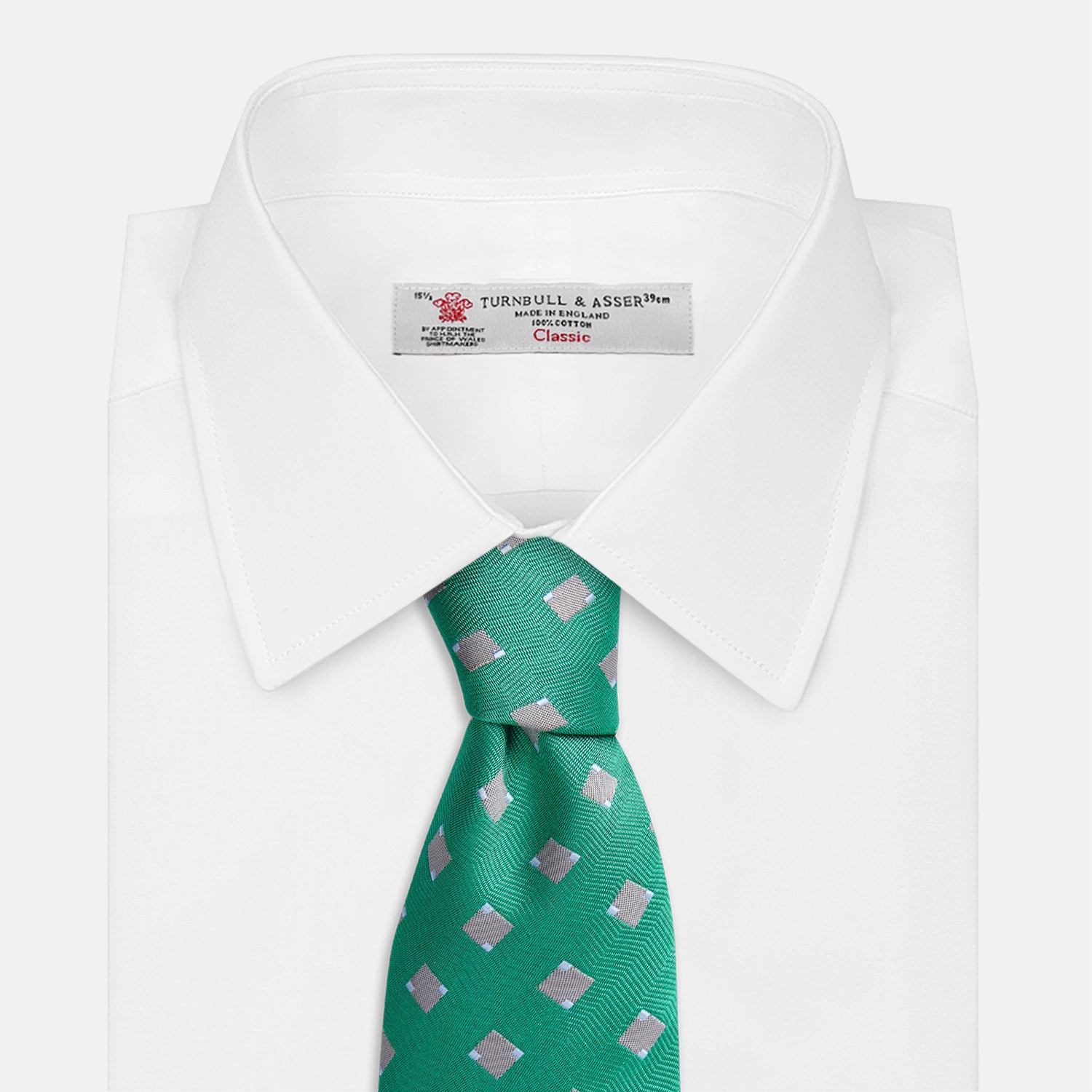 View 4 of product The Turnbull & Asser Kelly Green and Grey Tile Silk Tie features a subtle chevron texture and classic grey tile pattern, displayed rolled on a white background.