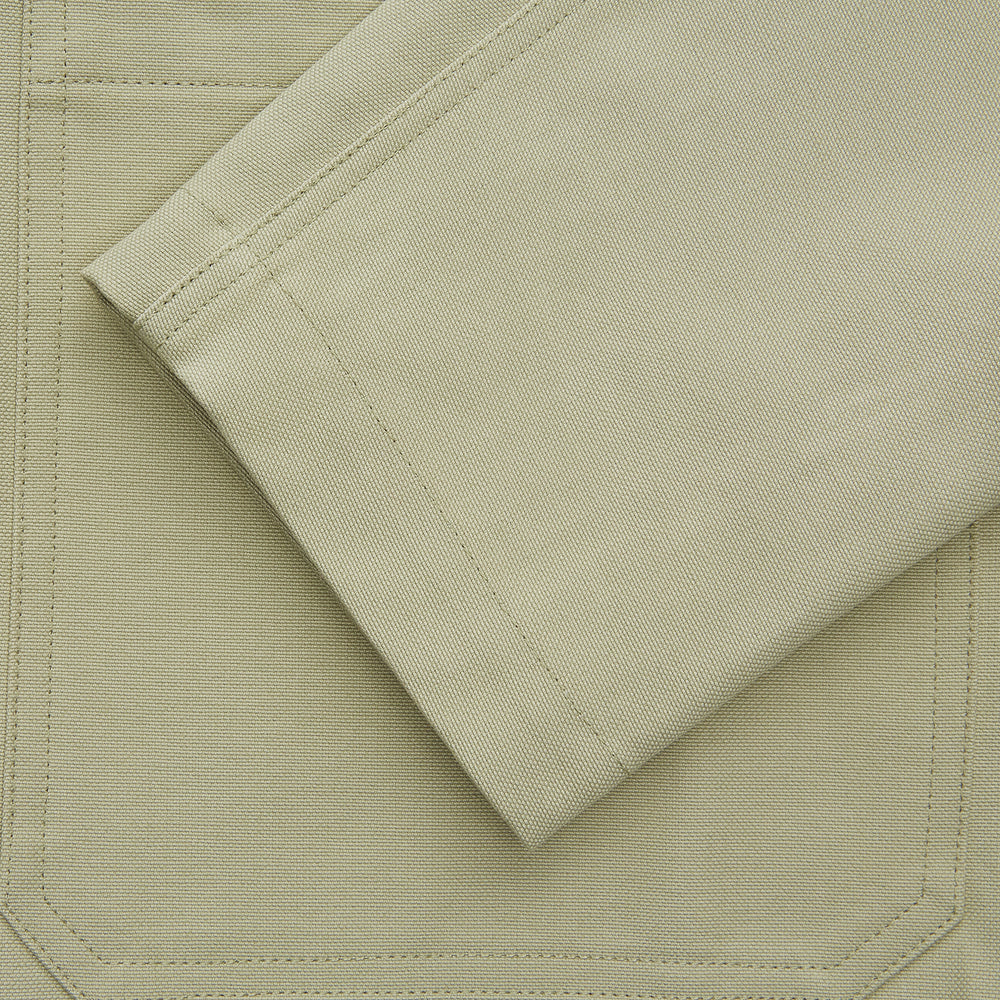 The Turnbull & Asser Tan Organic Cotton Blend Remy Chore Jacket features long sleeves, a collar, button-down front, and three pockets—an essential for any men’s wardrobe. The jacket is shown laid flat on a white background.
