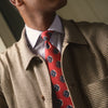 View 2 of product A rolled-up Red Shadow Spot Printed Silk Tie by Turnbull & Asser, showcasing large navy blue and white circular motifs, displayed on a plain white background.