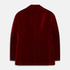 View 4 of product The Turnbull & Asser Wine Velvet Barrington Blazer, tailored in Italy, features a deep red hue, notched lapel, two front buttons, three pockets, and cuff button details. Shown against a plain white background.