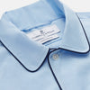 View 2 of product The Turnbull & Asser Light Blue Piped Cotton Nightshirt is a luxurious long-sleeve shirt dress with a pointed collar, black piping on the collar, cuffs, and chest pocket, button front closure, and curved hem.