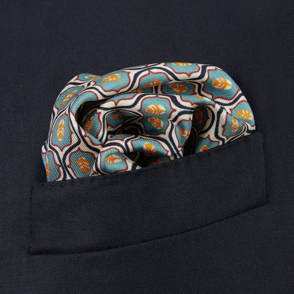 The Turquoise Flower Bloomsbury-Inspired Pattern Silk Pocket Square by Turnbull & Asser features a vibrant geometric floral motif with a turquoise border for a colorful, symmetrical accent.