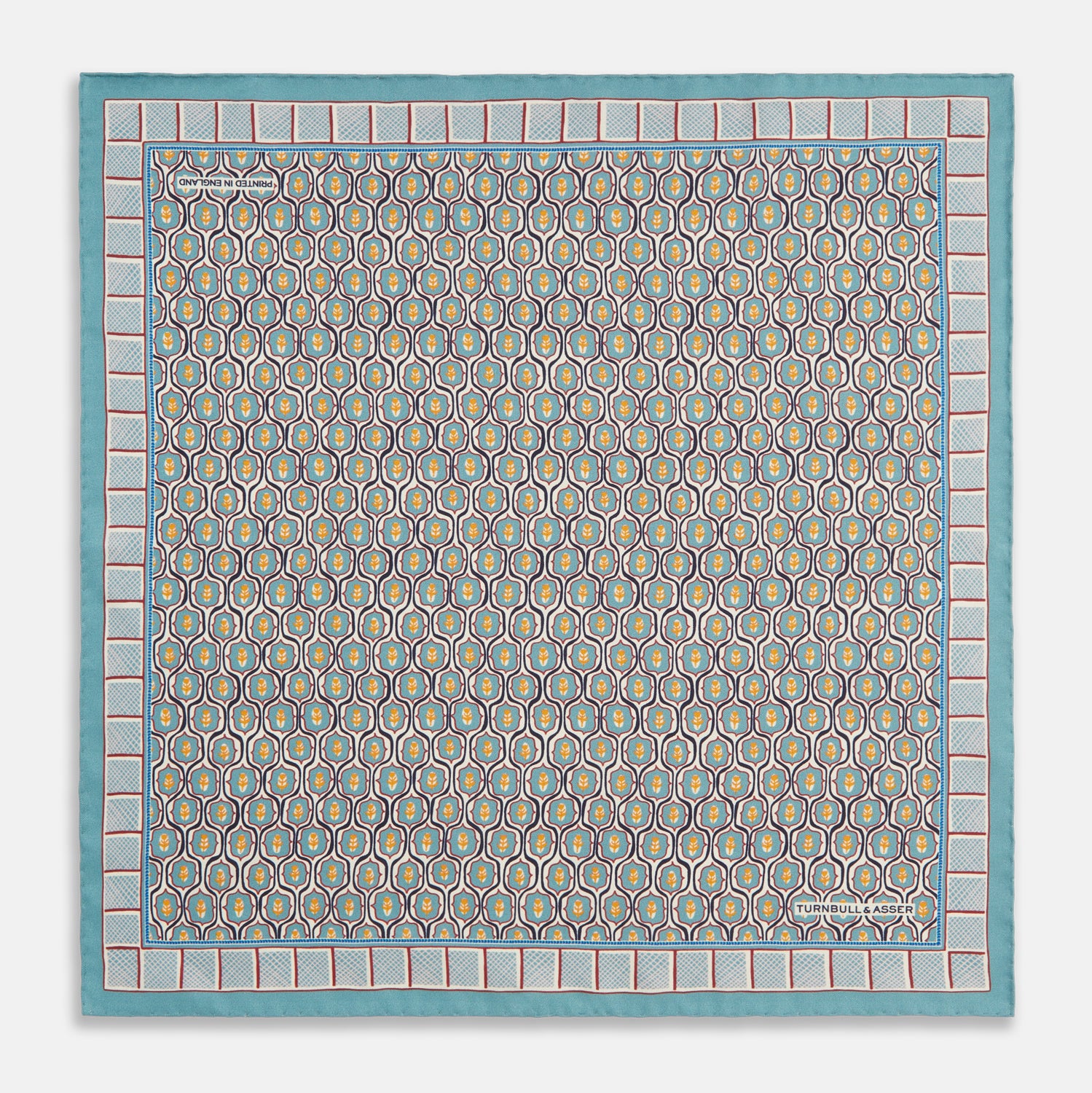 View 1 of product The Turquoise Flower Bloomsbury-Inspired Pattern Silk Pocket Square by Turnbull & Asser features a vibrant geometric floral motif with a turquoise border for a colorful, symmetrical accent.