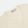 View 2 of product The Turnbull & Asser Cream Cashmere V-Neck Jumper is a luxury knitwear piece with ribbed cuffs and hem, shown laid flat on a white background. Its classic long-sleeve style offers timeless elegance.