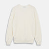 View 3 of product The Turnbull & Asser Cream Cashmere V-Neck Jumper is a luxury knitwear piece with ribbed cuffs and hem, shown laid flat on a white background. Its classic long-sleeve style offers timeless elegance.