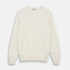 View 1 of product The Turnbull & Asser Cream Cashmere V-Neck Jumper is a luxury knitwear piece with ribbed cuffs and hem, shown laid flat on a white background. Its classic long-sleeve style offers timeless elegance.