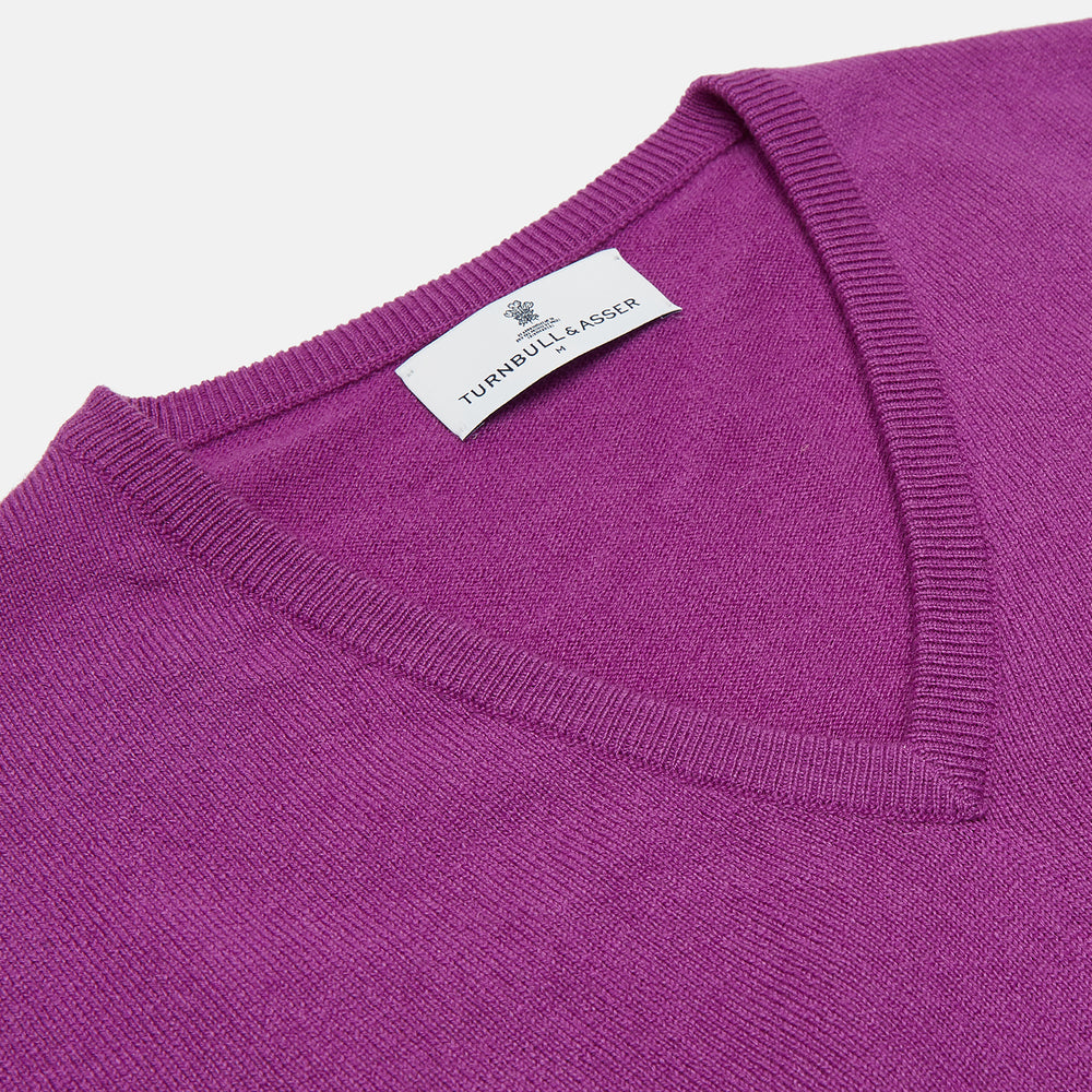 The Turnbull & Asser Magenta Cashmere V-Neck Jumper features long sleeves, ribbed cuffs, and a ribbed hem, shown against a plain white background.