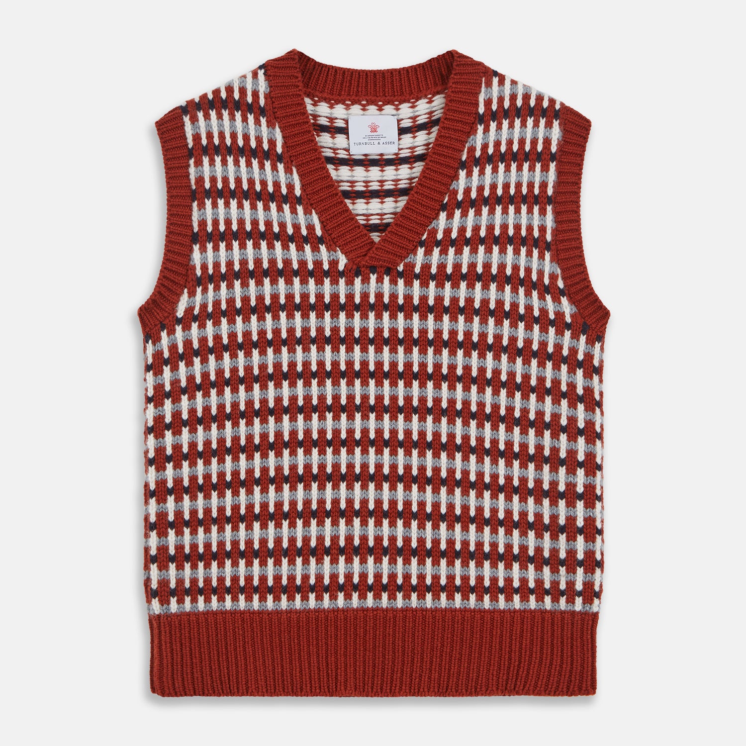 View 1 of product The Rust Knitted Cashmere Slipover by Turnbull & Asser is a sleeveless V-neck vest in red, white, and dark brown houndstooth, inspired by Welsh knitwear with solid red ribbed trim at the collar, armholes, and hem.