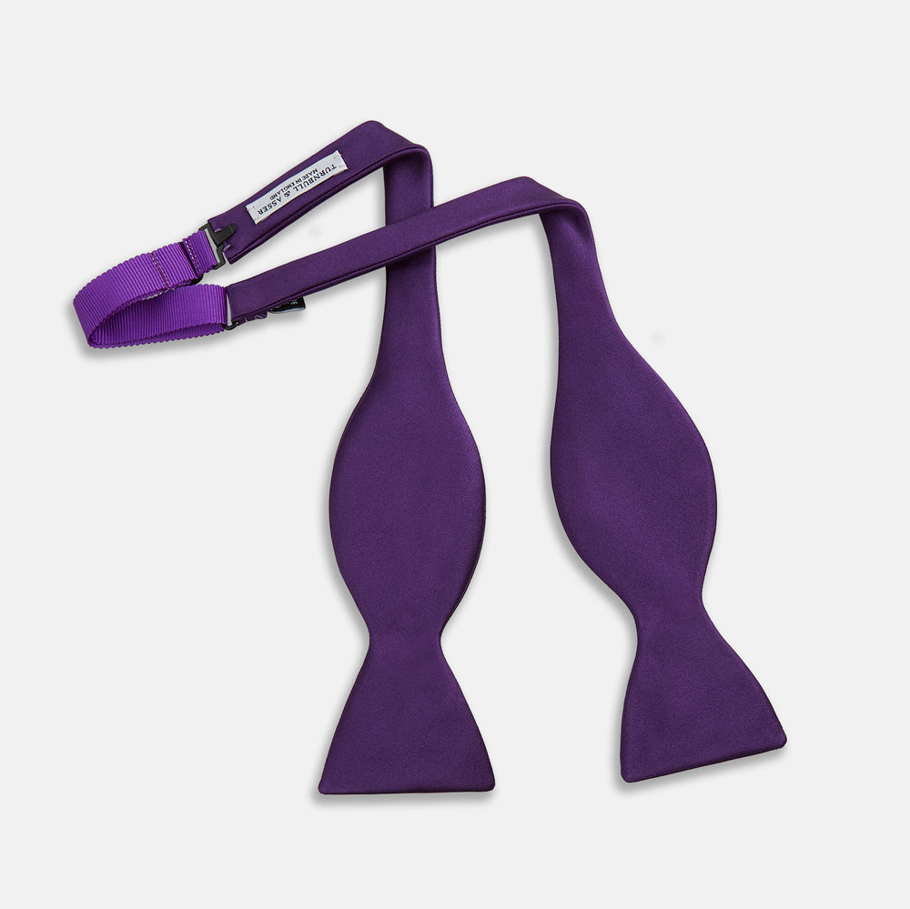 The Turnbull & Asser Plum Plain Satin Silk Bow Tie features a smooth texture and is neatly tied, displayed against a plain white background.